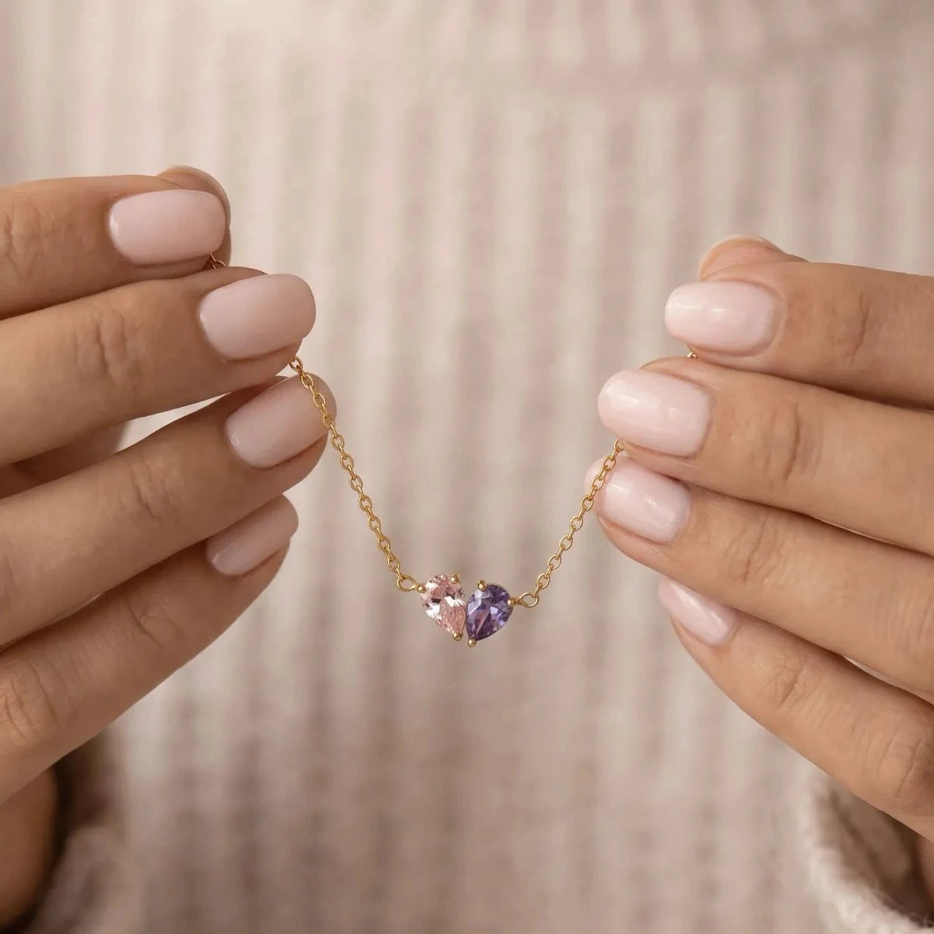 Gold Lori Bracelet held in hands, pink and purple birthstones